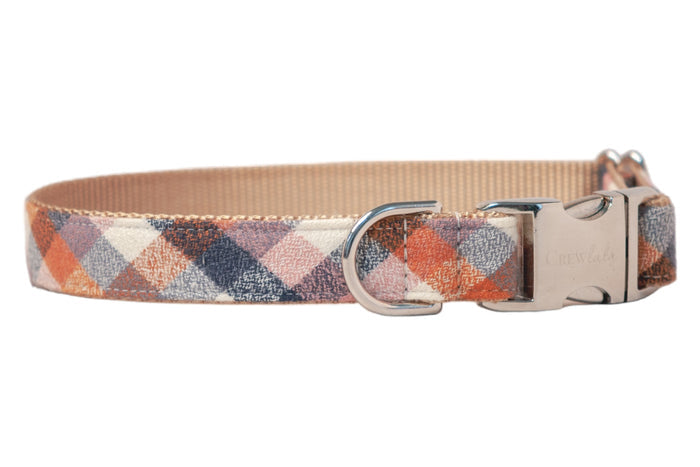 A stylish flannel dog collar in a rich autumn plaid pattern, featuring intersecting diamond shapes. The collar is reinforced with beige nylon webbing and fitted with metal hardware, including a D-ring and branded buckle.