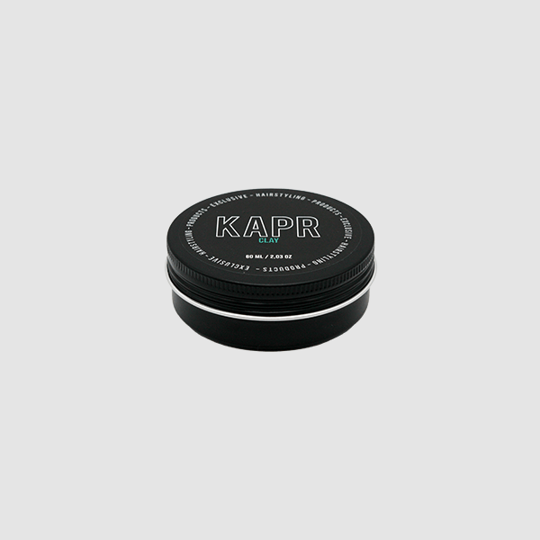 KAPR Clay – zwarte pot met wit logo en blauwe tekst op grijze achtergrond, matte hairstyling clay.