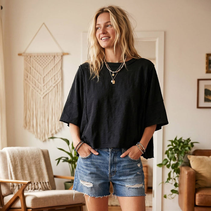 Woman wearing a black t-shirt and denim shorts standing in a living room.
