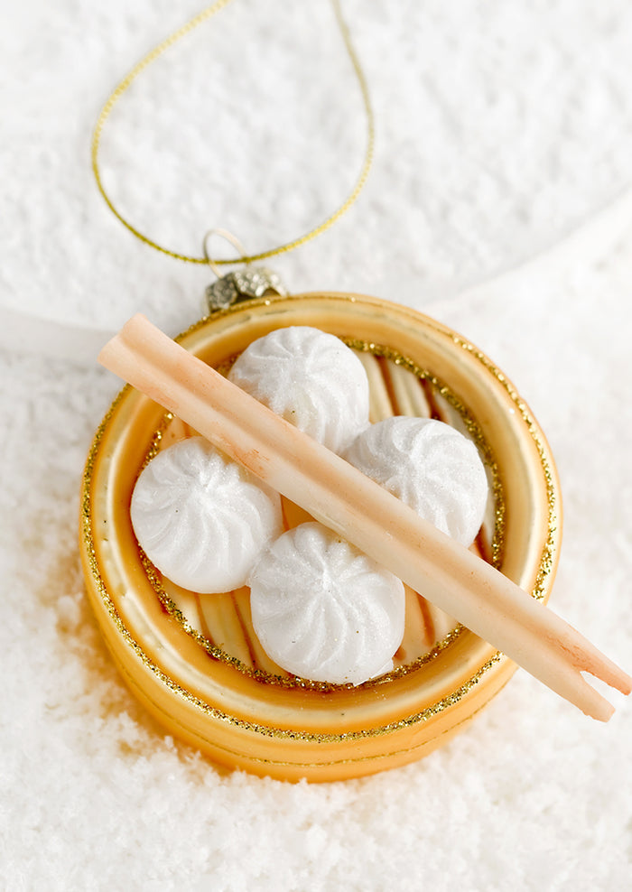 A glass ornament of tray of steamed buns with chopsticks.
