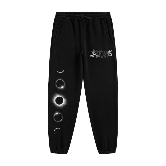 Kittie black sweatpants made from recycled polyester, featuring a moon phase graphic with four lunar stages on one leg and a white ornate logo near the pocket, shown on a plain white background.