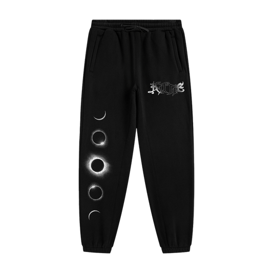 Kittie black sweatpants made from recycled polyester, featuring a moon phase graphic with four lunar stages on one leg and a white ornate logo near the pocket, shown on a plain white background.