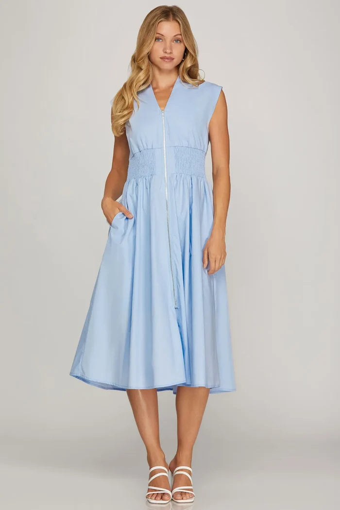 Woman wearing a light blue sleeveless dress with a zipper on a gray background