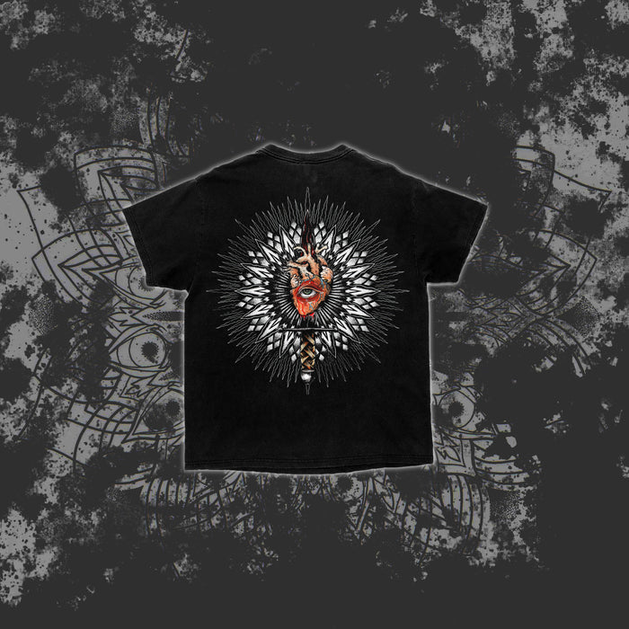 A black Reflections t-shirt features an ornate sunburst mandala with a detailed mask-like face at the center, set against a dark patterned background—ideal for fans of unique printed tees.