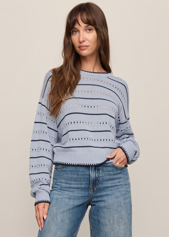 Woman wearing a blue and navy striped sweater with jeans