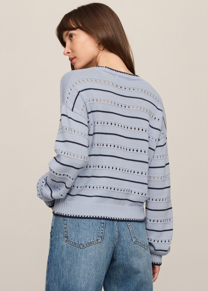 Woman turned around wearing a blue and navy striped sweater with jeans