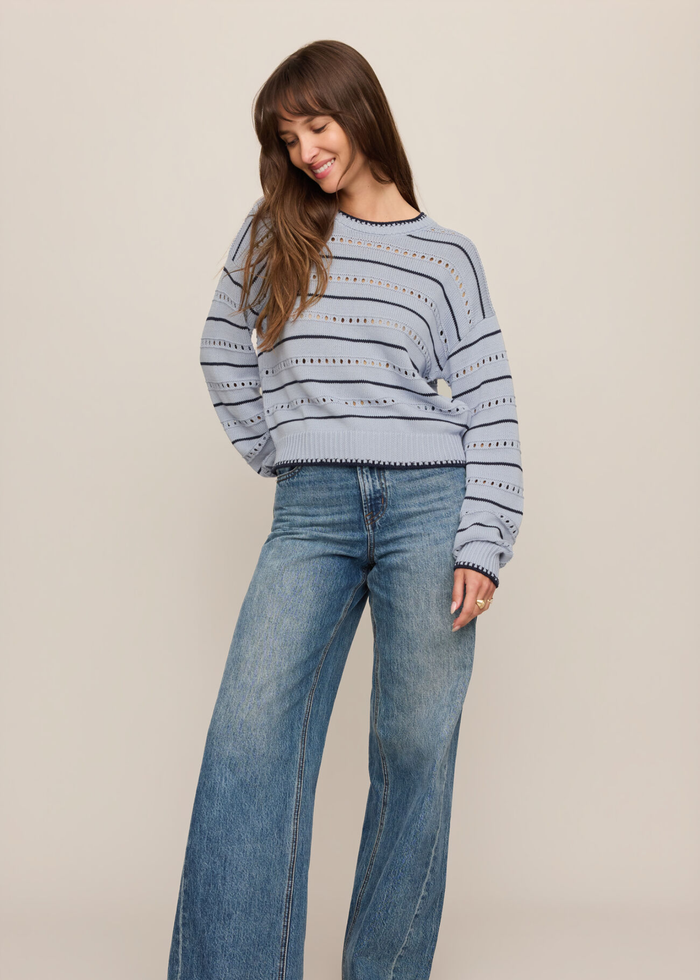 Woman wearing a blue and navy striped sweater with jeans